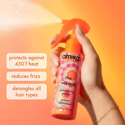 Image 1 - A hand holding a spray bottle of Amikas the wizard detangling primer against an orange background, with visible text that reads protects against 450°F heat, reduces frizz, and detangles all hair types.
Image 2 - A colorful bottle of amika detangling primer titled the wizard is displayed beside an avocado half with a brown pit, surrounded by orange sea buckthorn berries and oil drops, with text that reads SEA BUCKTHORN nourishes hair and AVOCADO OIL promotes moisture + smoothing benefits.
Image 3 - Image shows a vibrant display of haircare products from amika, including a detangling spray labeled the wizard, two bottles labeled normcore signature shampoo and normcore signature conditioner, a bottle of perk up dry shampoo, and a jar labeled soulfood nourishing mask, all set against an orange tiled background with descriptions highlighting their uses: detangle + heat-protect, for nourishing cleanse + condition, moisturize + soften, and absorb oil + reduce odor.
Image 4 - Image shows two bottles of Amikas the wizard detangling primer side by side, with the left bottle featuring a black spray nozzle and a colorful design, and the right bottle with an orange spray nozzle; visible text includes from that above the left bottle, to this above the right bottle, and the wizard detangling primer had a makeover! PACKAGING MAY VARY below.
Image 5 - A woman is shown with her hair styled on the right side and unstyled on the left side, with text above stating the wizard detangling hair primer and below saying protects hair against heat up to 450°f.
Image 6 - A smiling person with pink hair is shown in a before-and-after comparison, with the left side displaying frizzy hair labeled BEFORE and the right side showing smooth hair labeled AFTER, alongside the text the wizard detangling hair primer and protects hair against heat up to 450°f.
Image 7 - Two colorful hair product bottles from Amika, one orange and one pink, with spray tops, labeled as the wizard and featuring text indicating they are detangling primers, with information about ingredients like avocado oil and squalane; a caption above reads pick your styling potion.