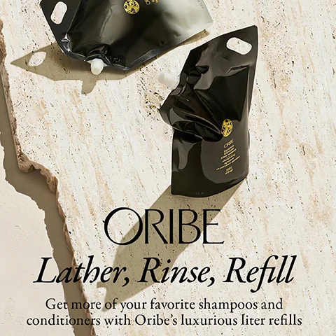 Two black Oribe liter refill pouches are shown on a textured surface with the text ORIBE Lather, Rinse, Refill Get more of your favorite shampoos and conditioners with Oribe’s luxurious liter refills.