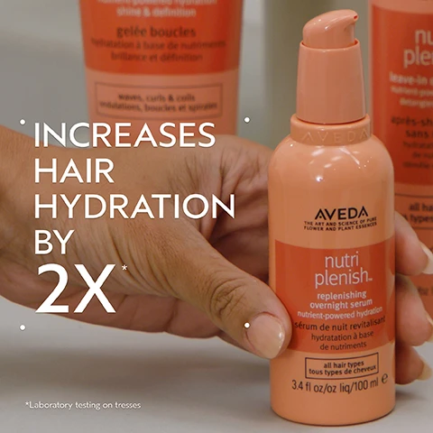 Image 2 - A close-up of a hand holding a peach-colored Aveda Nutriplenish overnight serum bottle with a pump dispenser, with other blurred Aveda products in the background, and overlay text that reads Increases Hair Hydration By 2X* *Laboratory testing on tresses, along with text on the bottle stating AVEDA THE ART AND SCIENCE OF PURE FLOWER AND PLANT ESSENCES nutri replenish. replenishing overnight serum nutrient-powered hydration sérum de nuit revitalisant hydratation à base de nutriments all hair types tous types de cheveux 3.4 fl oz/oz liq/100 ml e. Image 3 - A dark green background features a large central circle containing an abstract image of swirling red and gold liquids, with white text SUPERFOOD COMPLEX, Lorem Ipsum, POMEGRANATE SEED OIL, COCONUT OIL, MANGO BUTTER, Hydrates and replenishes dry, depleted hair. Image 4 - A split image shows a woman with dark curly hair before and after a treatment: on the left, labeled BEFORE, her hair appears frizzy and less defined, with text Unwashed Hair below; on the right, labeled AFTER, her hair is smooth, shiny, and has more defined curls, with text below stating Results with Nutriplenish ™ Shampoo and Conditioner: Deep Moisture, Nutriplenish Leave-In Conditioner, Curl Gelee, Replenishing Overnight Serum and Wooden Paddle Brush. Blow dried with diffuser attachment. Image 5 - Close-up of a creamy, off-white substance with smooth, wavy textures and subtle highlights. Image 6 - The image presents a three-step hair care routine titled HOW TO USE, featuring Step 01 CLEANSE with a person washing their hair with Nutriplenish™ Shampoo: Deep Moisture; Step 02 CONDITION showing hands dispensing Nutriplenish™ Conditioner: Deep Moisture & Leave-In Conditioner from a tube labeled conditioner nutrient-powered hydration après-shampooing à base de nutriments 8.5 fl oz/oz liq/250 ml e; and Step 03 STYLE depicting hands dispensing Nutriplenish™ Curl Gelee & Replenishing Overnight Serum from a tube labeled gelee gel pour les boucles curl gelee 6.7 fl oz/200 ml e. Image 7 - The image shows three white certification logos on a dark green leafy background with a red plant stem on the left. The logos read: 100% VEGAN with a V symbol, Certified B Corporation with a B symbol, and a leaping bunny logo with Cruelty Free INTERNATIONAL.