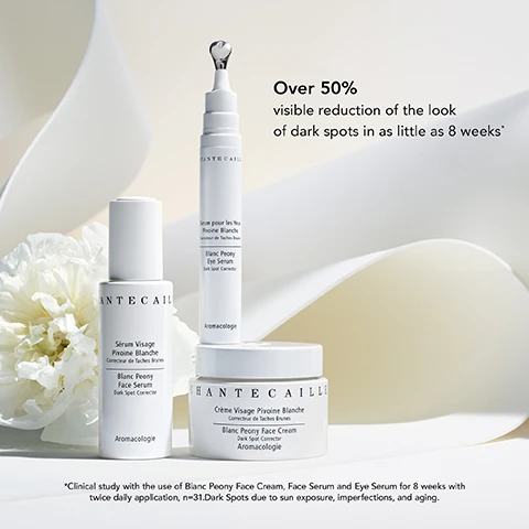 Image 1 - Three skincare products from Chantecaille are displayed on a soft, light background, including a face serum, an eye serum, and a face cream, with a white peony flower partially visible; text on the image reads Over 50% visible reduction of the look of dark spots in as little as 8 weeks.
Image 2 - A close-up image of a person gently touching their face with one hand, showcasing smooth skin and a subtle expression, with text that reads 54% visible reduction of the look of dark spots in as little as 8 weeks*.