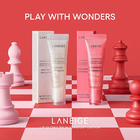 Two Laneige Lip Glowy Balms, one shimmery white and one shimmery pink, are displayed with their boxes on a red and pink checkered chessboard surrounded by matching chess pieces, along with the text PLAY WITH WONDERS, LANEIGE LIP GLOWY BALM BAUME BRILLANT POUR LES LÈVRES MILKY WAY VOIE LACTÉE Net Wt. 0.35 oz. Poids net 10 g, LANEIGE LIP GLOWY BALM BAUME BRILLANT POUR LES LÈVRES PINK SUPERNOVA PINK SUPER SUPERNOVA ROSE Net Wt. 0.35 Poids net 10, and LANEIGE LIP GLOWY BALM STARDUST EDITION.